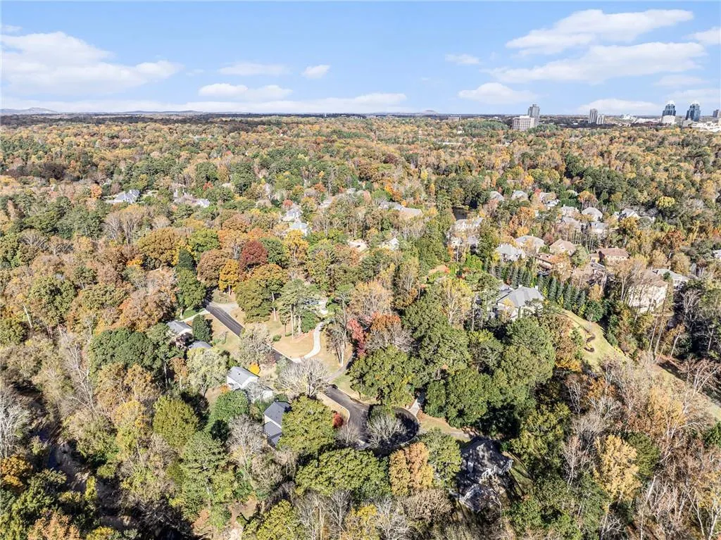 Aerial view of property and surrounding area with a heavily wooded area