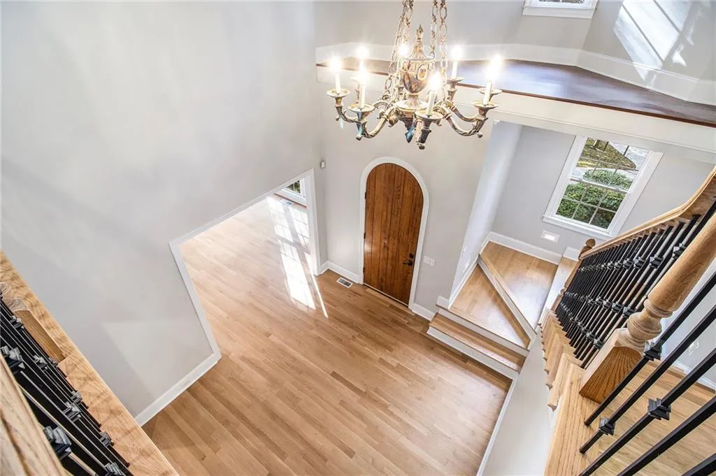 Entrance foyer featuring a towering ceiling, arched walkways, wood finished floors, a chandelier, and stairs