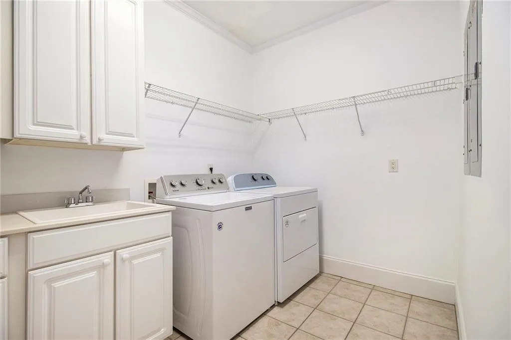 Laundry room with light tile patterned floors, crown molding, cabinet space, and separate washer and dryer
