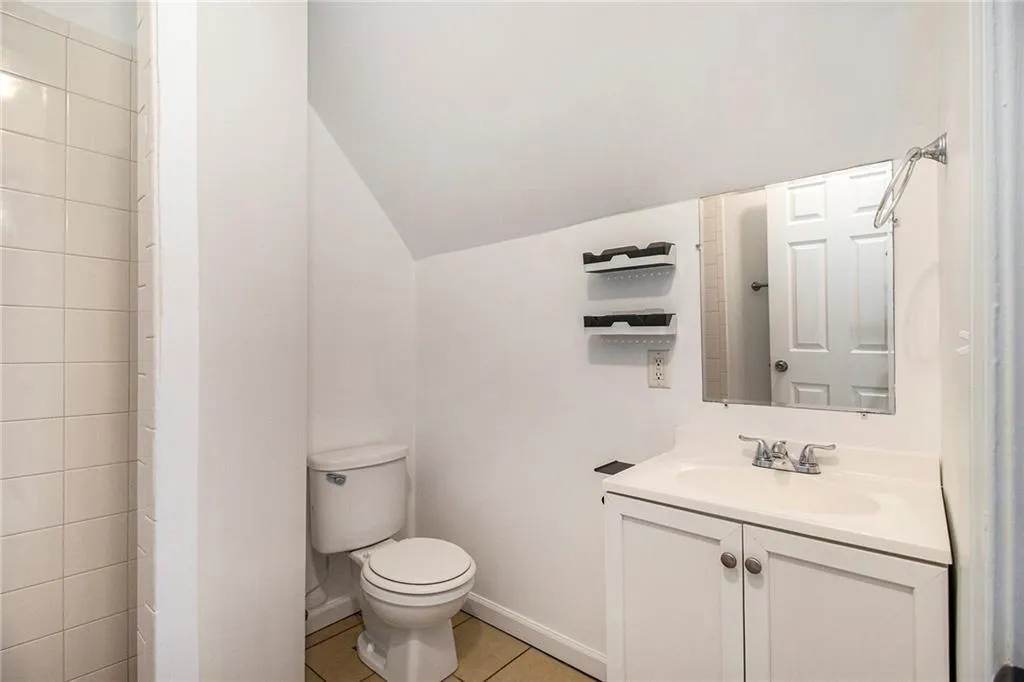 Bathroom with lofted ceiling, light tile patterned flooring, and vanity