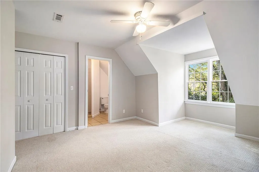 Additional living space featuring light colored carpet, lofted ceiling, and ceiling fan