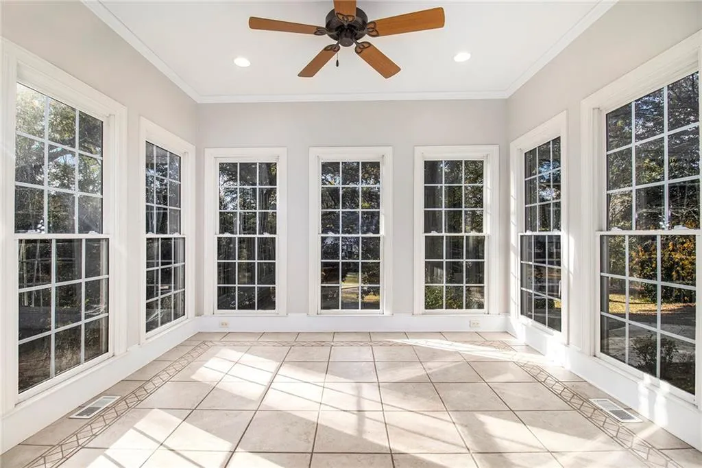 Unfurnished sunroom with tile patterned floors, inlaid floor details, ornamental molding, and recessed lighting