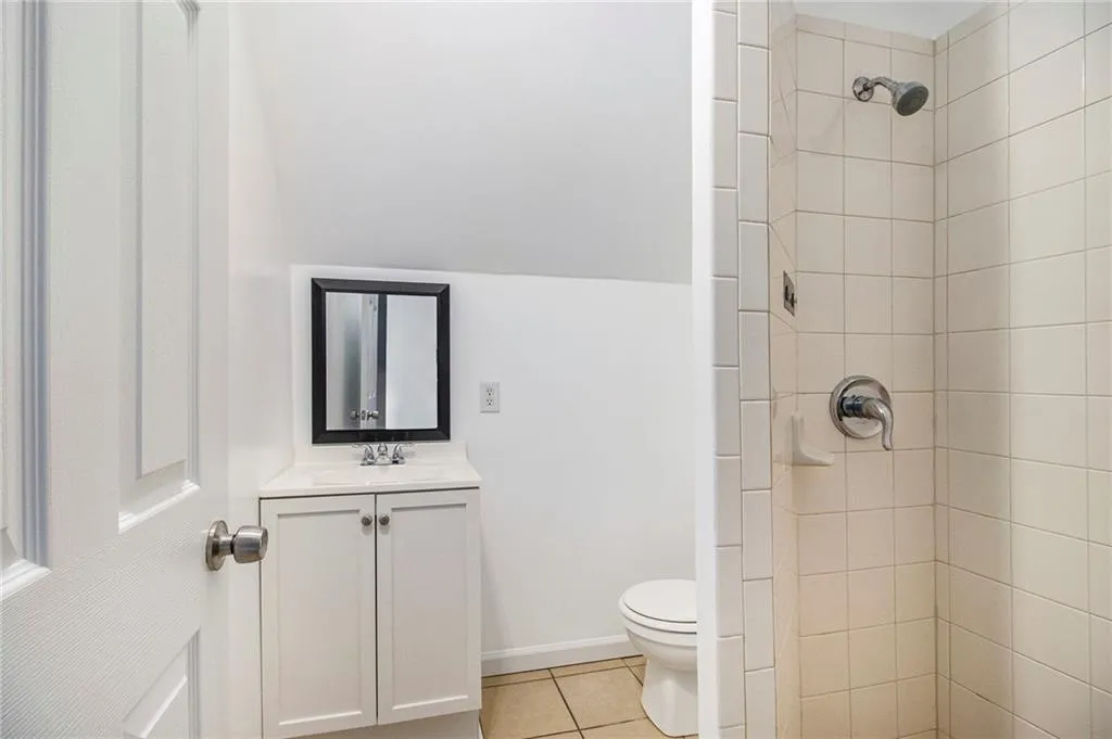 Full bath with vanity, light tile patterned flooring, and a shower stall