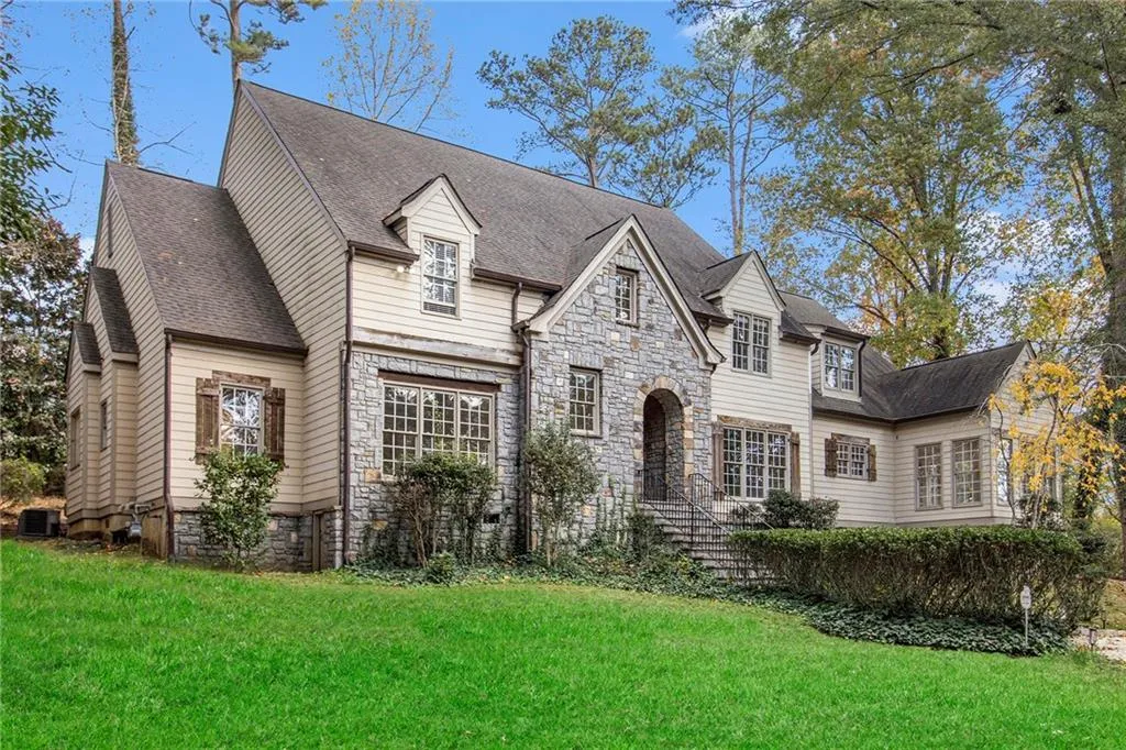 View of front of home with stone siding, a front yard, and a shingled roof