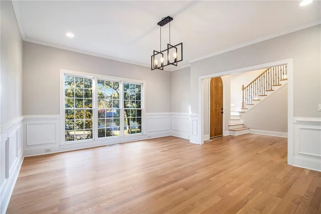 Unfurnished dining area with recessed lighting, stairway, crown molding, light wood-type flooring, and a chandelier