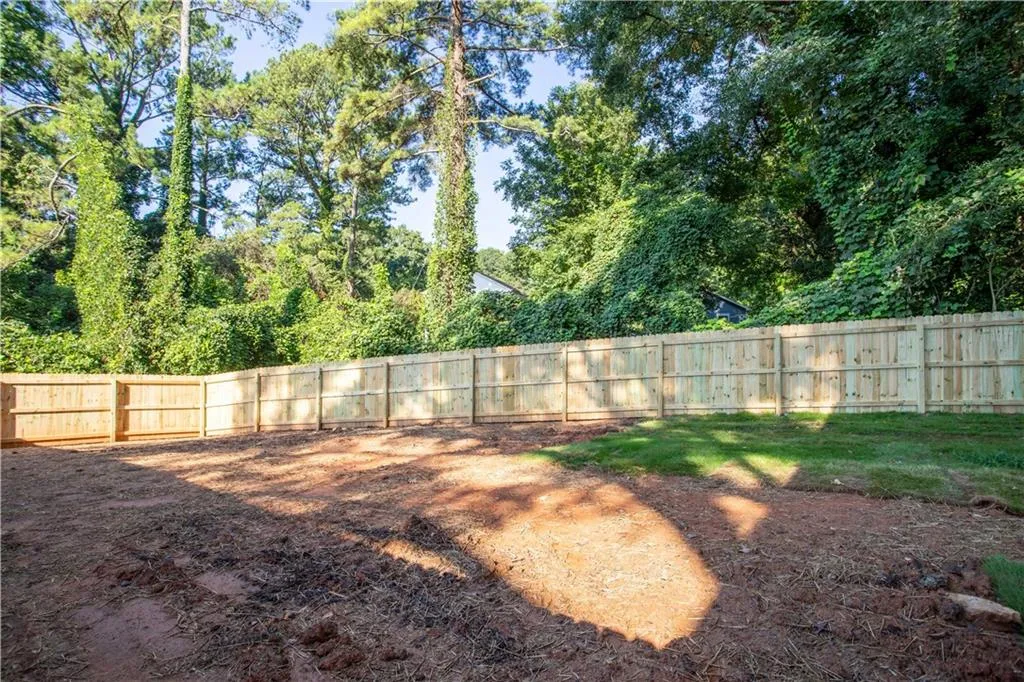 Expansive rear yard with a newly installed wood privacy fence and mature perimeter landscaping