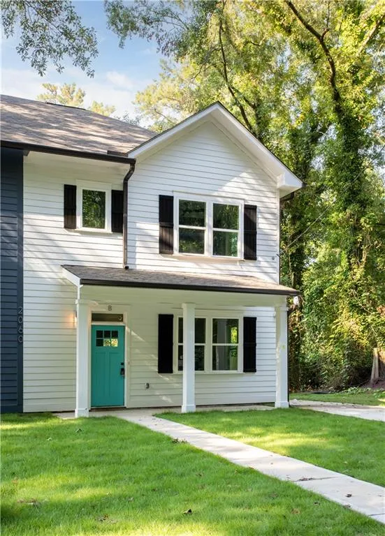 White siding exterior with black window shutters and a vibrant teal front door