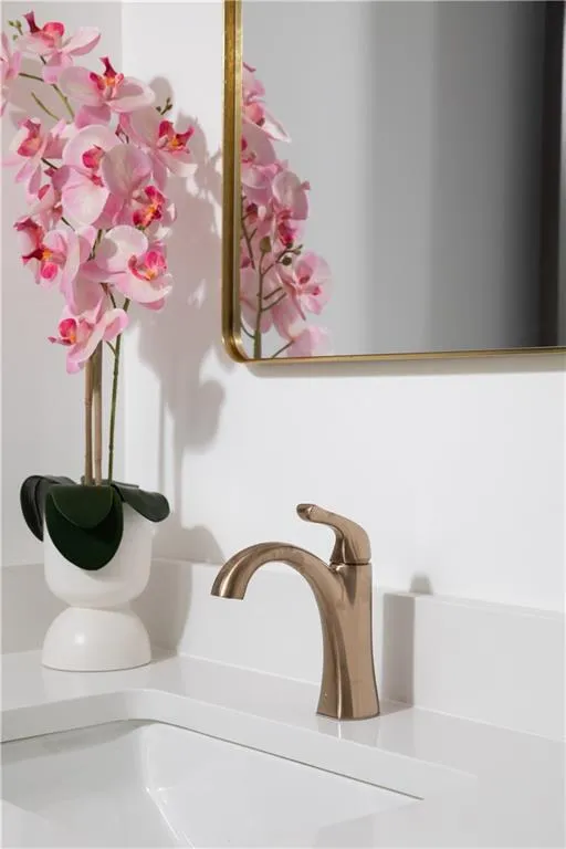 Undermount sink with a single-hole faucet in a brushed finish, set into a white countertop with an integrated backsplash