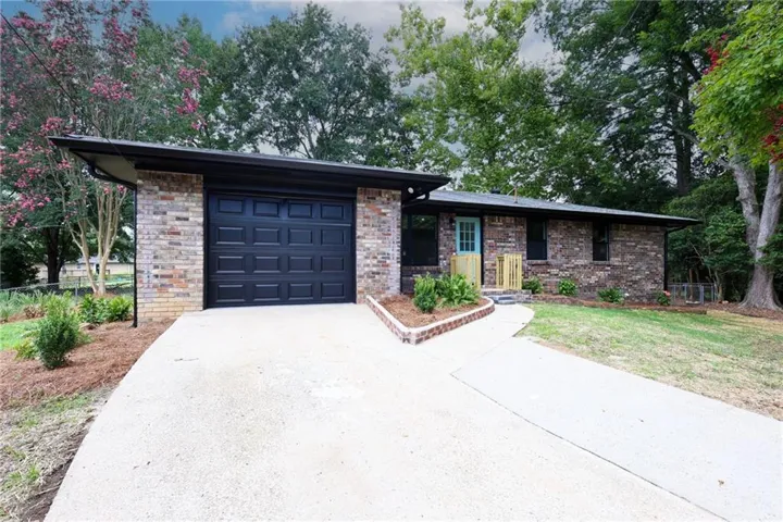 Brick exterior with a black garage door and an accent-colored entry door