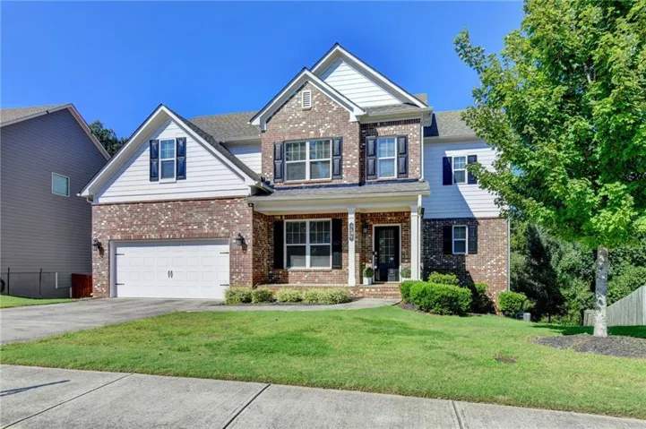 Brick and siding exterior with a covered porch, attached two-car garage, and established landscaping