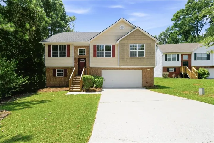 Split-level home featuring a brick and siding facade, a two-car garage, and a concrete driveway