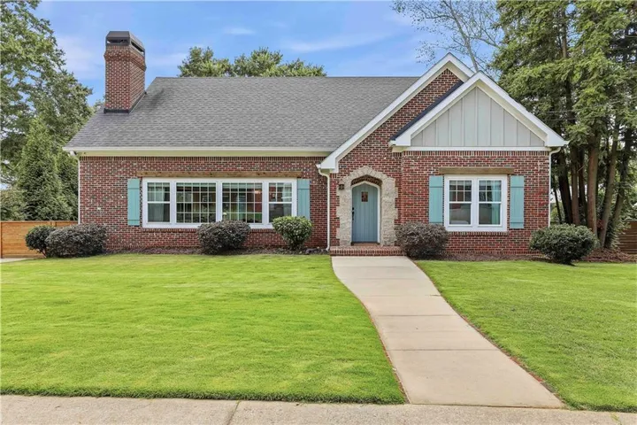 Brick exterior with a prominent chimney, a gabled roofline, and a light blue front door