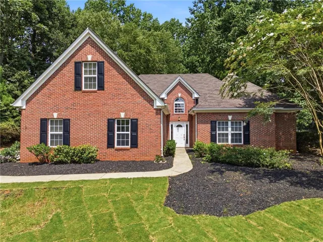 Brick exterior with contrasting dark shutters, a white paneled front door, an arched transom window, and a gabled roofline