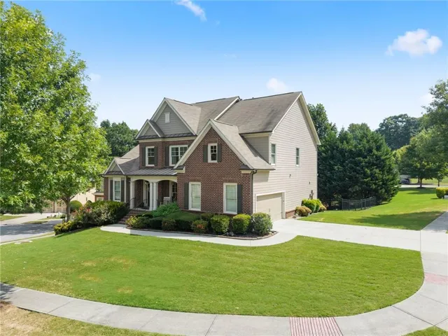 Brick facade with gabled roof lines, attached garage, covered front entry, and mature landscaping