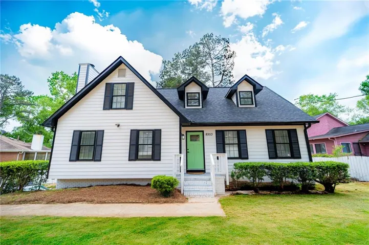 White siding exterior featuring a bright green front door, dark-framed windows, and black shutters