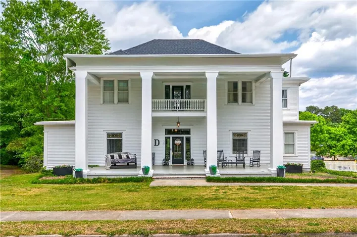 White Colonial Revival residence featuring a full-width front porch and upper balcony supported by prominent square columns