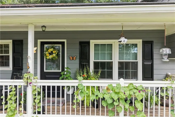 Covered porch with white railings, gray siding, and black window shutters