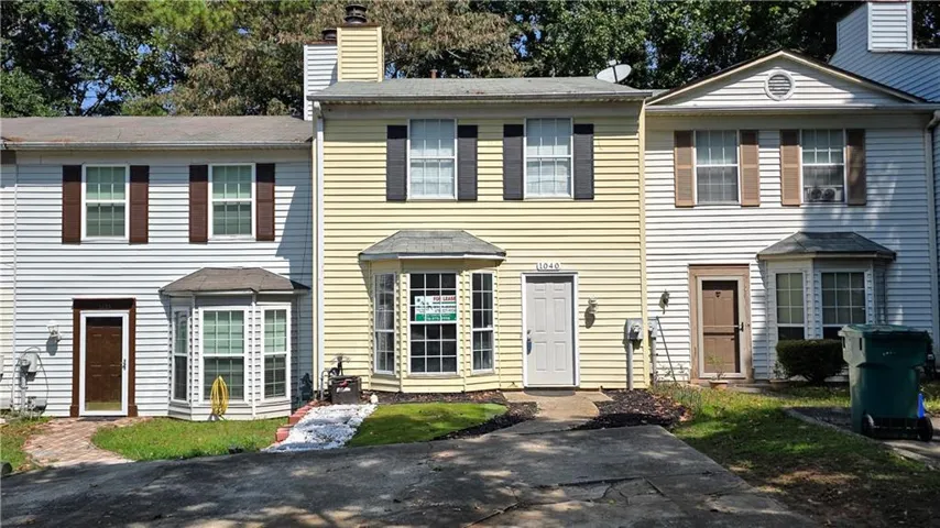 Yellow siding exterior with a bay window, white entry door, and black shutters