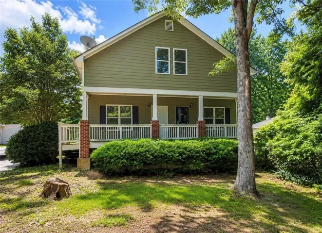 Two-story residence featuring a covered front porch with brick column bases and white railing