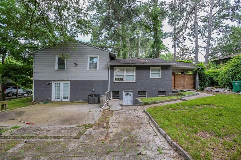 Rear view of property with french doors, a lawn, and brick siding