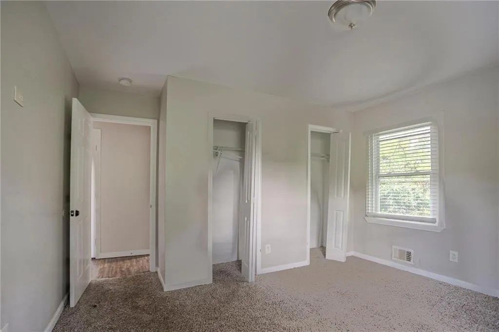 Unfurnished bedroom featuring multiple closets and carpet flooring