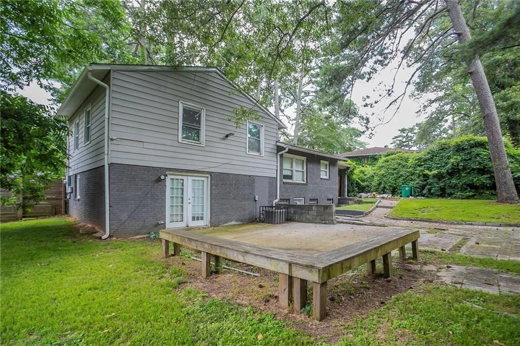 Rear view of house featuring french doors, a yard, a wooden deck, and brick siding