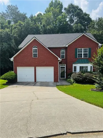 Two-story brick residence featuring a two-car garage, multiple arched windows, and a bay window with a green awning