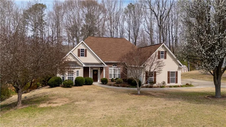 Siding exterior with brick accents, dormer windows, and a brown shingle roof