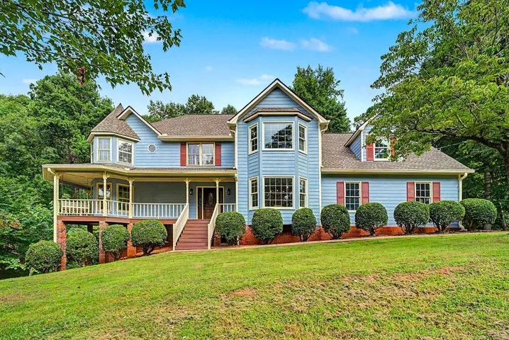 Expansive front lawn with mature landscaping, a wraparound porch, bay windows, and a multi-level architectural design