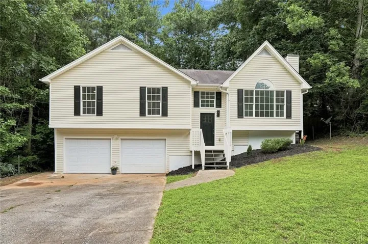 Split-level residence featuring light-colored siding and a contrasting dark entry door