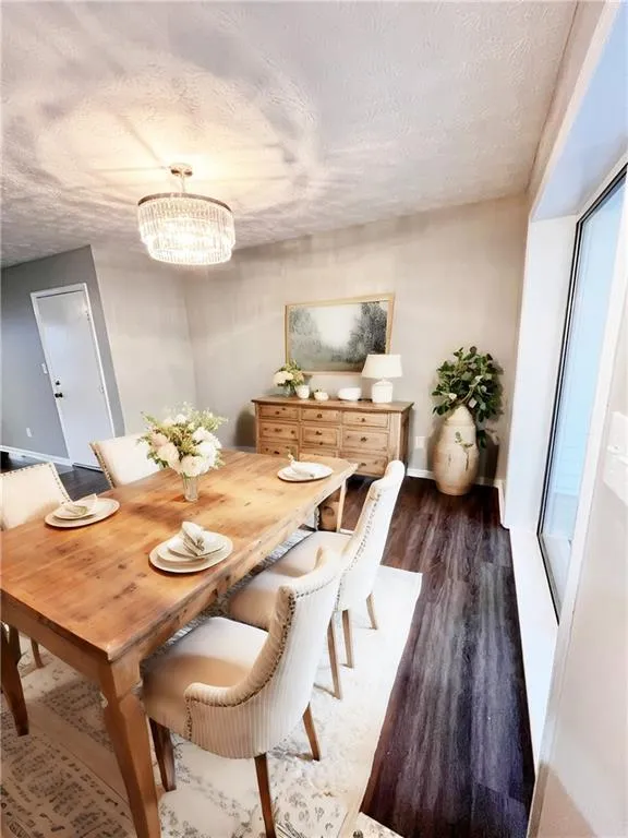 Dining space with dark hardwood / wood-style floors, a textured ceiling, and a chandelier - Virtual Staging