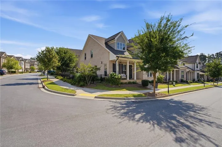 Brick facade with dormer window, covered front porch, and mature landscaping