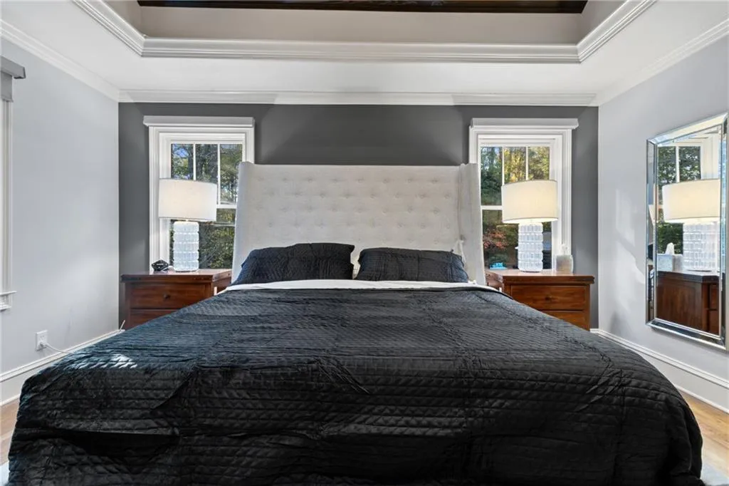 Bedroom with multiple windows, wood finished floors, and crown molding
