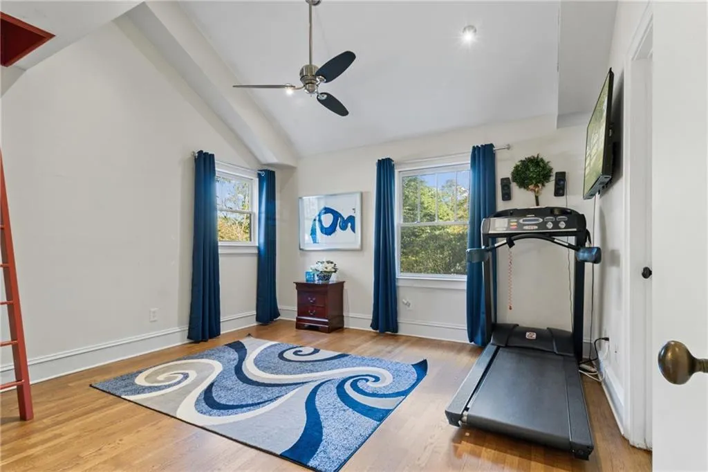 Workout area featuring light wood finished floors, a ceiling fan, and high vaulted ceiling