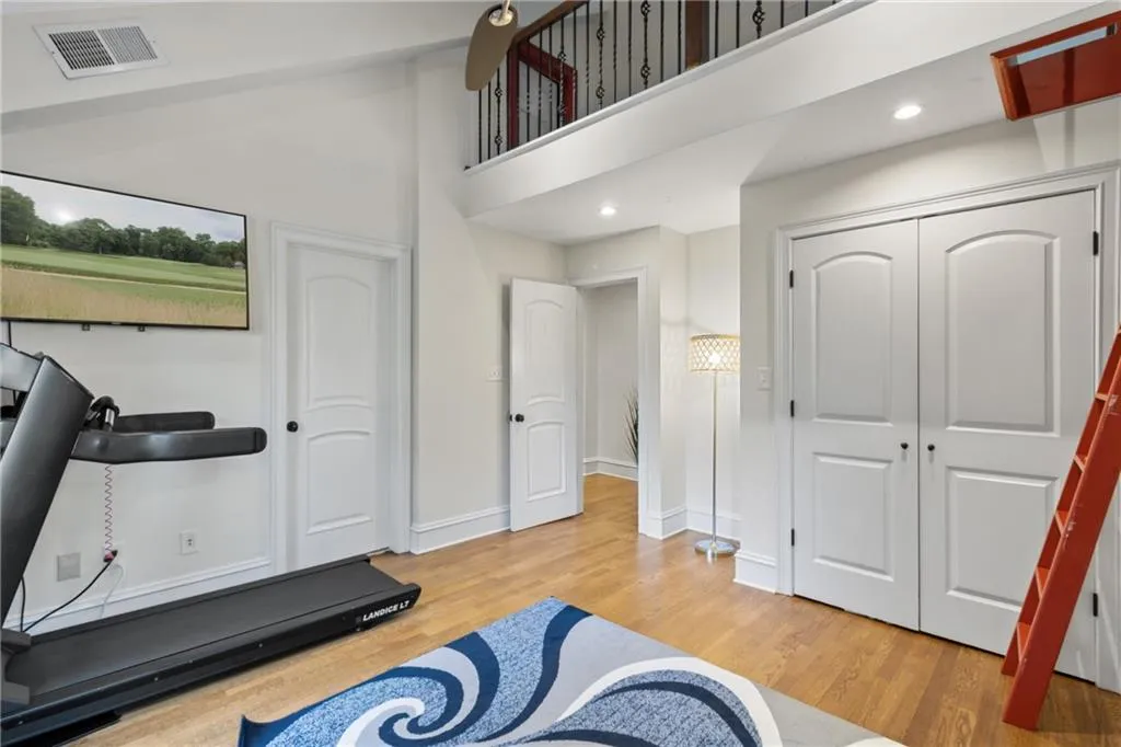 Exercise room featuring light wood-style floors, a towering ceiling, and recessed lighting