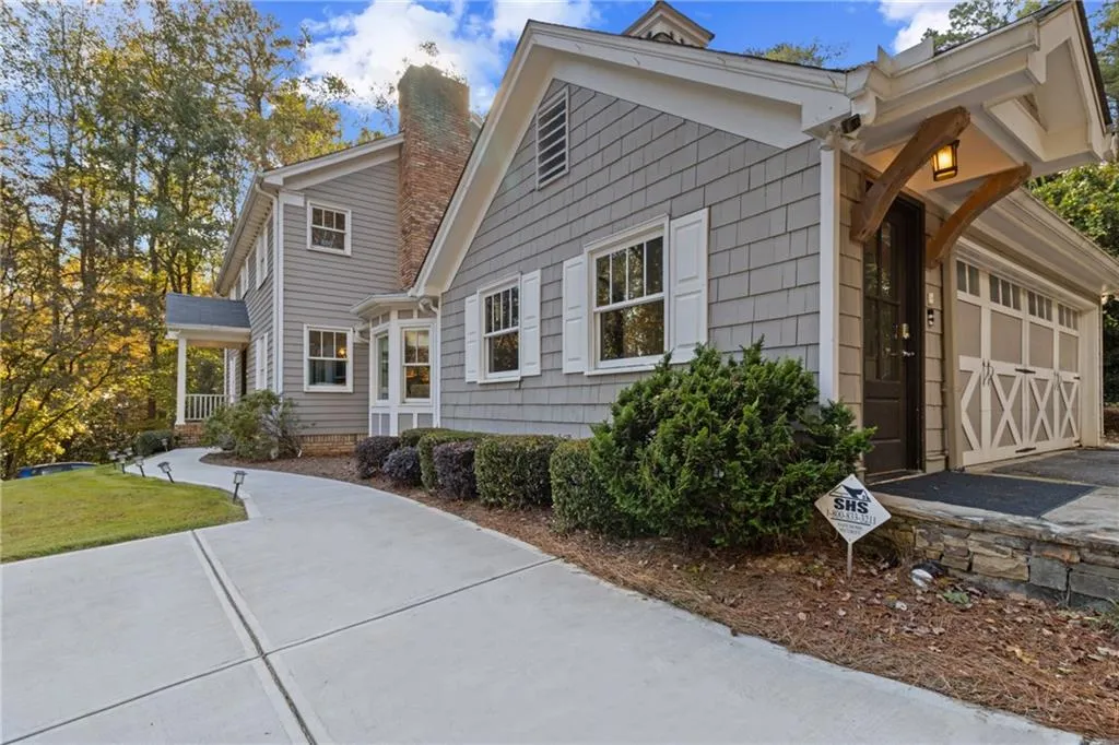 View of side of property featuring a chimney, driveway, and an attached garage