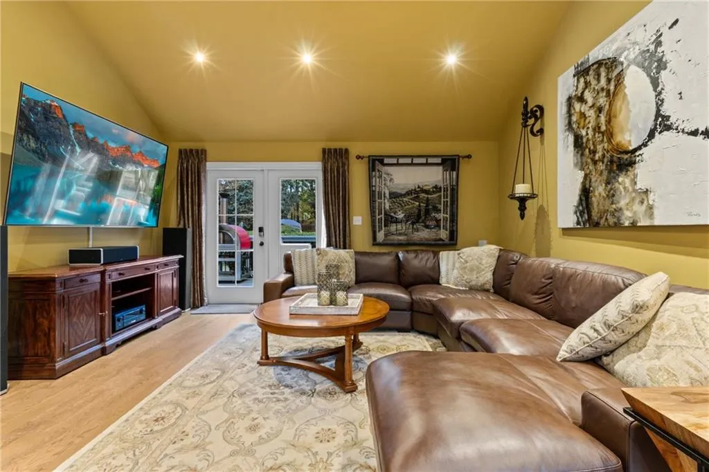 Living area featuring light wood-style floors, french doors, and vaulted ceiling