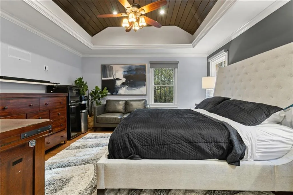 Bedroom featuring lofted ceiling, crown molding, wooden ceiling, wood finished floors, and ceiling fan