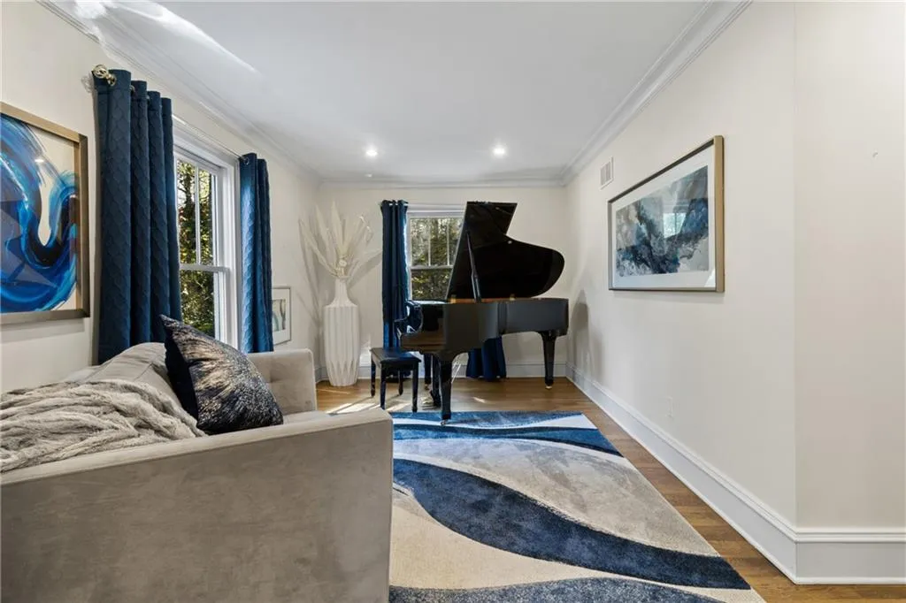 Sitting room with wood finished floors, ornamental molding, and recessed lighting