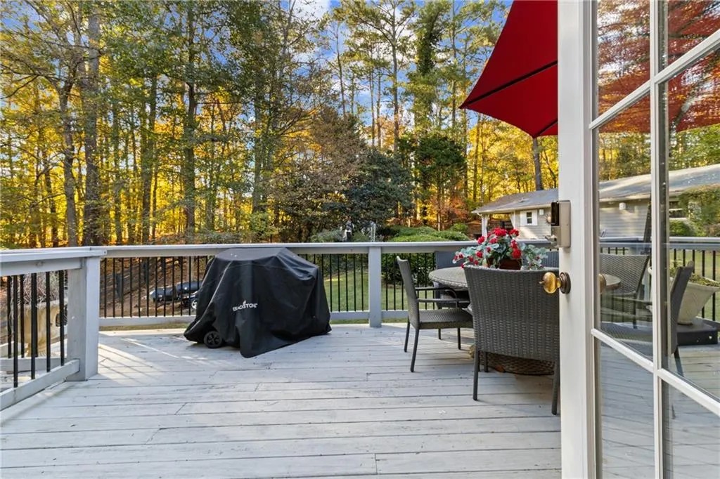 Deck featuring outdoor dining area, a grill, and view of scattered trees