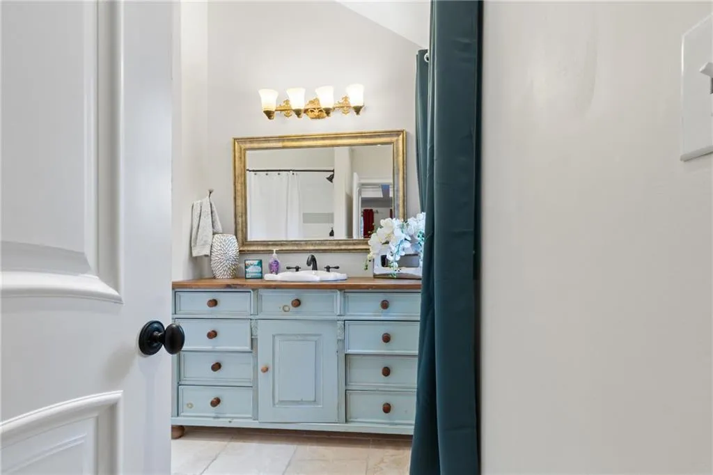 Bathroom with light tile patterned floors, vanity, and a shower with shower curtain