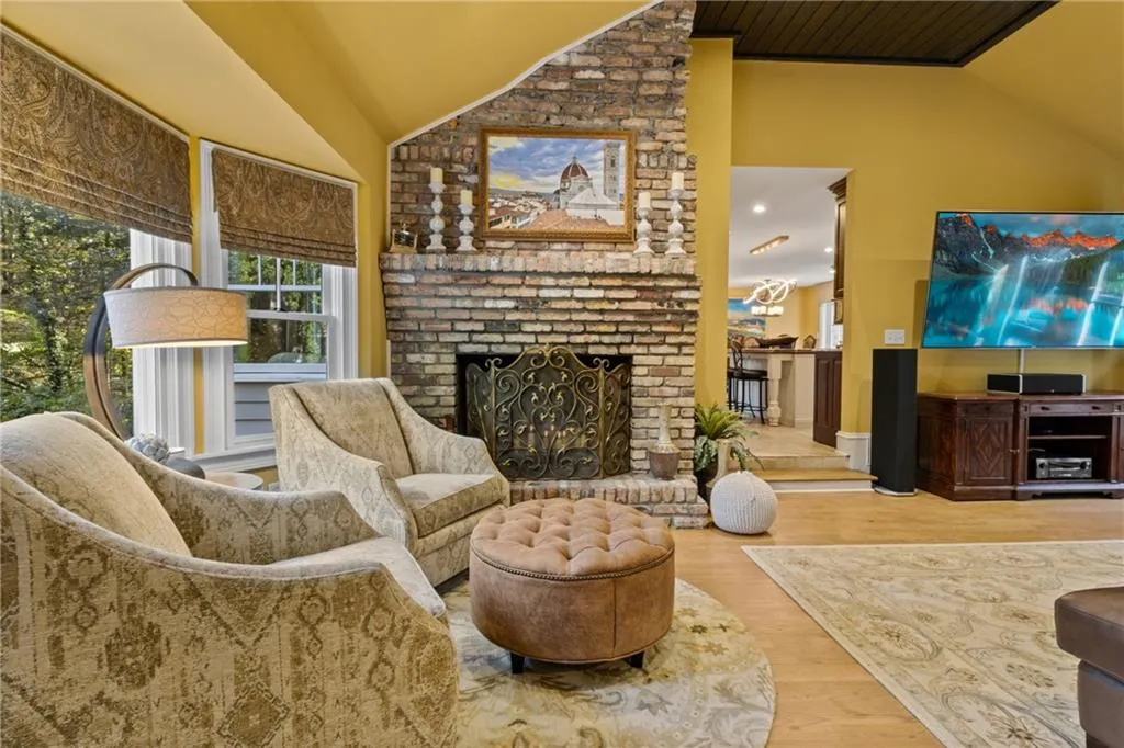 Living room with lofted ceiling, wood finished floors, and a fireplace