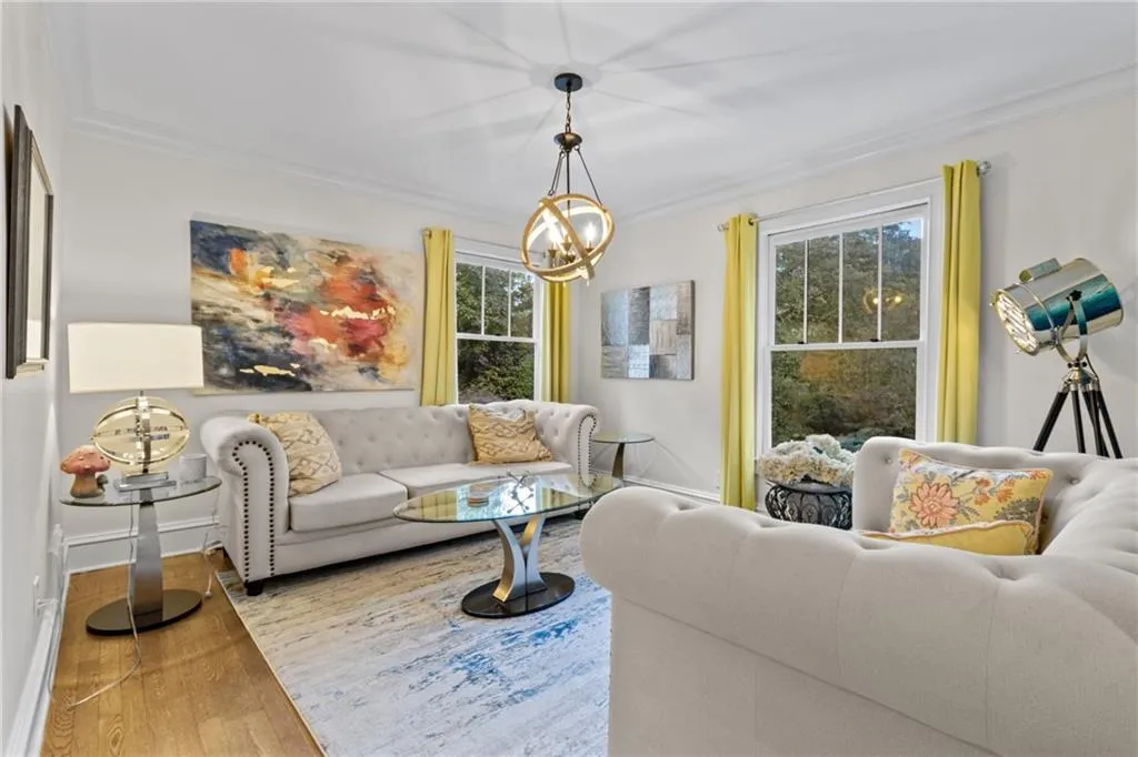 Living room featuring wood finished floors, a chandelier, and ornamental molding