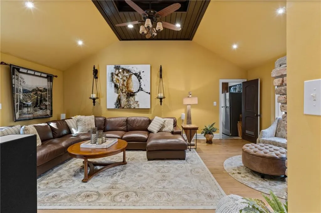 Living room with vaulted ceiling, wood finished floors, recessed lighting, and a ceiling fan