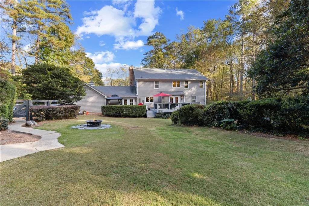 Rear view of property with a yard, an outdoor fire pit, and a chimney