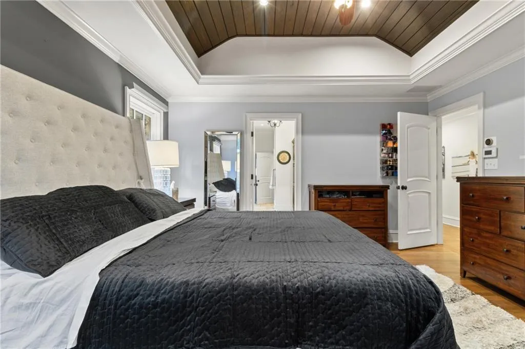 Bedroom featuring lofted ceiling, crown molding, wood finished floors, wood ceiling, and ensuite bathroom