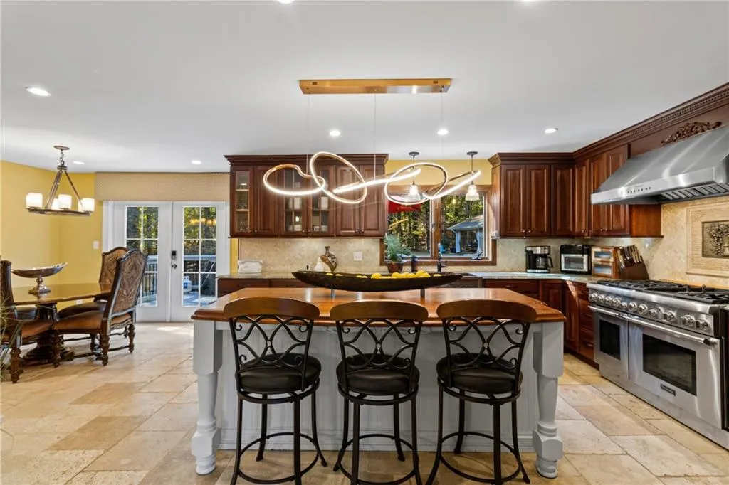 Kitchen featuring a chandelier, pendant lighting, stone tile floors, double oven range, and tasteful backsplash