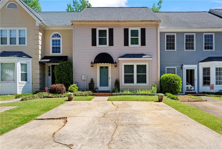 Two-story townhouse with light-colored siding and dark shutters