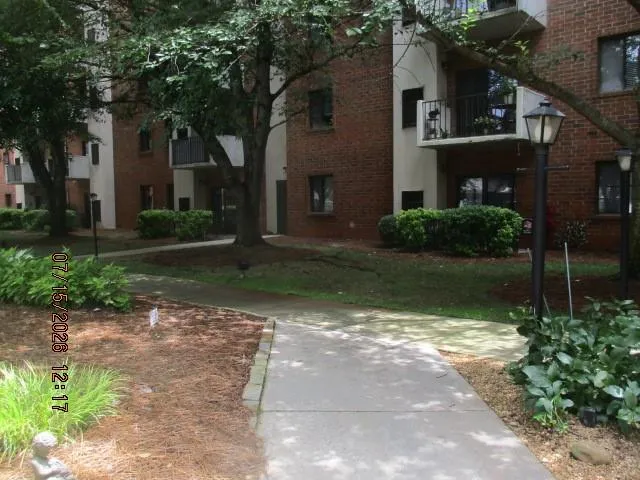 Brick apartment building with private balconies and mature trees