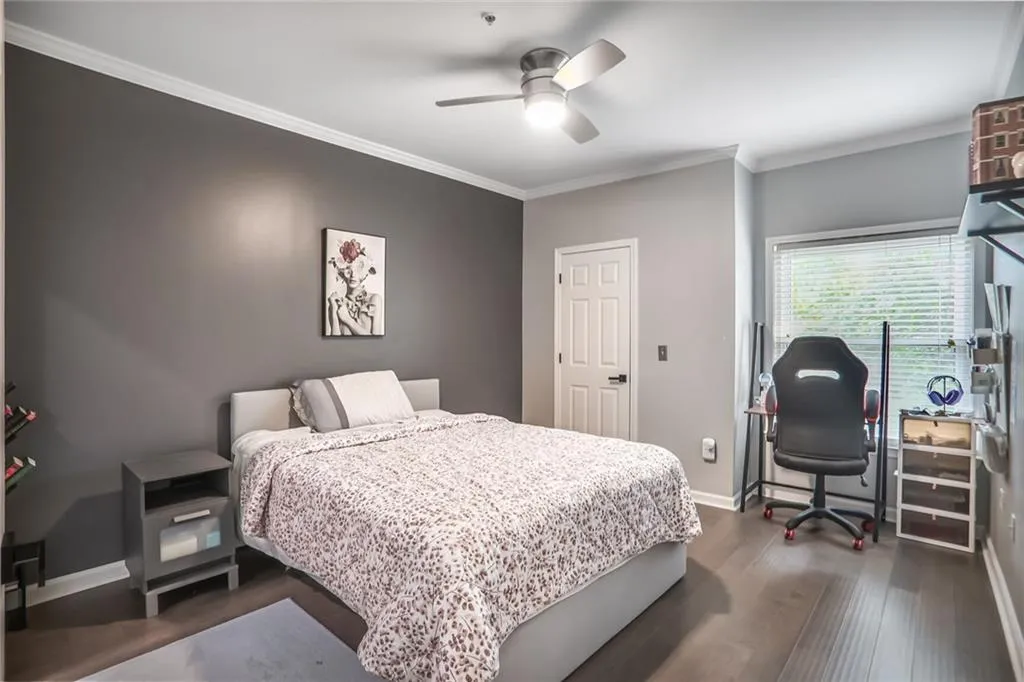 Bedroom with ornamental molding, dark wood-type flooring, baseboards, and ceiling fan